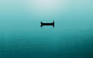 Silhouettes of the fishermen on the boat, among the beautiful, turquoise ocean