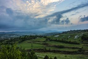 Beautiful landscape of the green mountains, with the plants, at colorful and beautiful sunrise in the sky, with the clouds