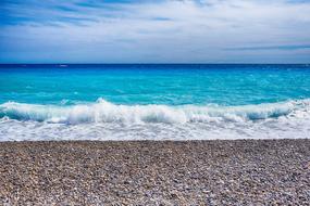 turquoise surf on a pebble beach on a sunny day