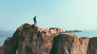 man on top of a cliff near the sea