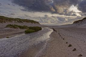Beautiful and colorful landscape of the shore of the North Sea, with the hills, in Denmark, under the clouds
