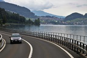 Car, driving on the beautiful highway, near the lake, among the colorful mountains in Switzerland
