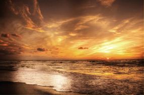 Beautiful and bright, gold sunset in the clouds above the sea with coast in Denmark