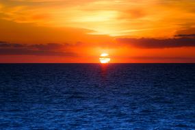 Beautiful waterscape with the blue water, at colorful, gradient sunset on horizon