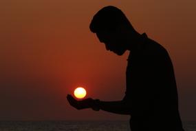 fantastic photo of a guy holding the evening sun on his hand