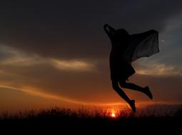 silhouette of a girl jumping at dusk