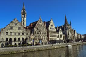 Beautiful shore of the canal, with the houses, in Ghent, Flanders, Belgium, at blue sky on background