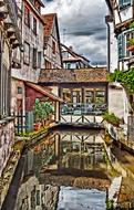 Beautiful water, among the colorful houses, with the plants, in France, under the sky with the clouds
