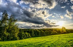 sunset in the clouds over rural green landscape