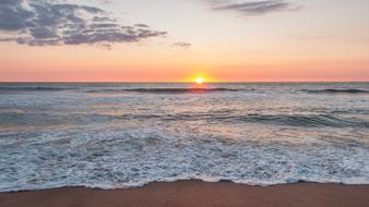 Beautiful, sandy coast of the sea in Denmark, at colorful sunset in the sky