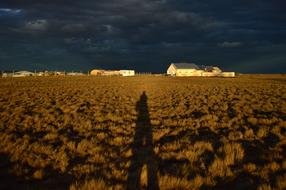 Beautiful landscape with the shadow of the person, near the houses, under the clouds