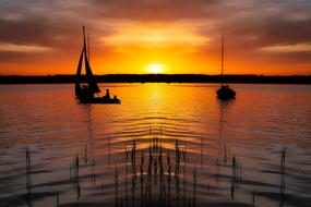 Beautiful waterscape with the boat silhouettes on Starnberger See, at colorful sunset in Bavaria, Germany