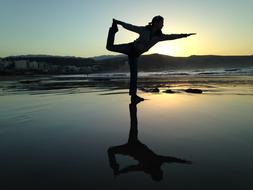 girl doing yoga on the beach at dusk
