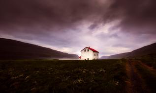 distant view of white house with red roof in iceland nature