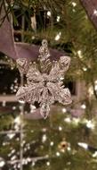 Beautiful, shiny Christmas snowflake on the green Christmas tree with lights