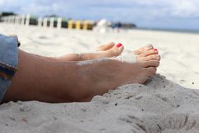 Feet with red nails in the sand