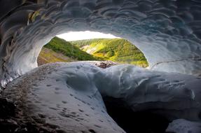 Beautiful landscape with the snow cave near the green mountains