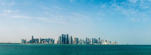 Cityscape of the city with the skyscrapers, among the colorful water, under the blue sky with clouds