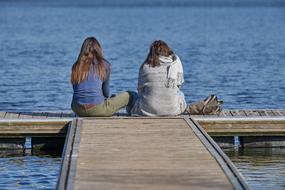 girls sit on the pier by the sea