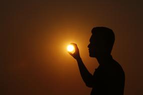 silhouette of a man with the sun in his hands