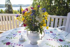 Close-up of the colorful and beautiful flowers, in the vase. on the table, with the colorful, patterned cloth