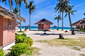 Beautiful landscape of the sandy beach, with the colorful plants and bungalows