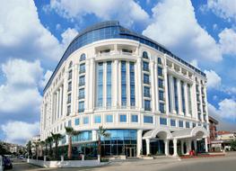 Beautiful, white hotel with blue windows, at blue sky with white clouds on background