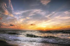 Beautiful beach of the North Sea in Denmark with waves, at colorful sunset