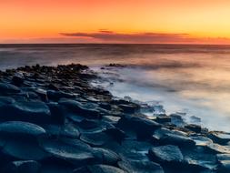 Beautiful coast of the ocean in Ireland, at colorful and beautiful sunset in the sky