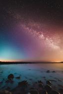 stones on the coast of the ocean against the sky with a colored glow