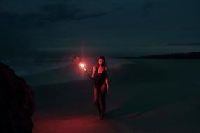 girl with a torch on the coast at night