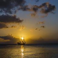 distant view from the beach to the sailing ship at dusk