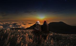 girl with an animal on a rock against the backdrop of the setting sun