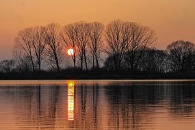 Beautiful landscape of the shore of the lake with reflections, and with plants, at colorful and beautiful sunset