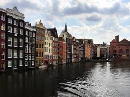 Beautiful landscape with the colorful houses on the shore in Amsterdam, Netherlands, under the clouds