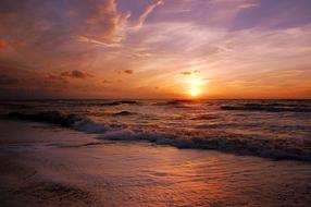Beautiful landscape of the beach with waves, at colorful and beautiful sunset in clouds