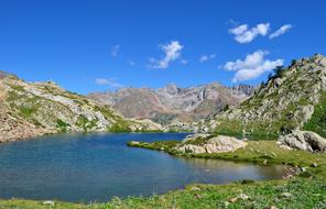 Beautiful landscape of the water, among the colorful mountains with rocks, under the blue sky with white clouds