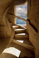 Spiral staircase in the building with window with sunlight, and shadows