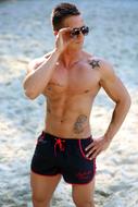 muscle man in black swimming trunks on the beach