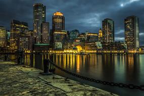 Cityscape with the buildings with lights, on the shore, under the clouds, in the evening, clipart