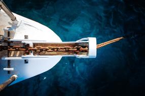 Close-up of the old, rusty anchor on the white boat, on the water with ripple