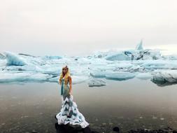 girl in a mermaid dress on the background of the icy sea in Iceland