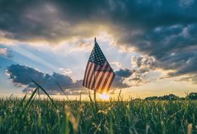 american flag on a green field at dusk