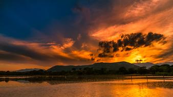 Beautiful landscape with the water, near the mountains, at colorful and beautiful sunset, among the clouds, in Corsica