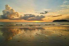 Beautiful landscape of the sandy beach near the water, at colorful and beautiful sunrise, among the clouds