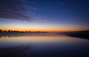 Beautiful and colorful landscape with the lake, among the trees, at colorful twilight