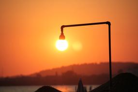 burning street lamp on the background of the orange sky during sunset