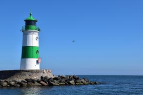 white-green lighthouse on the coast on a sunny day