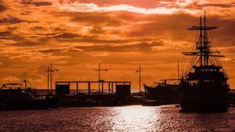 Harbor of the sea, with silhouettes and ship, in colorful and beautiful sunset