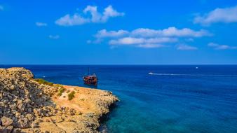 Colorful boat in the colorful and beautiful cape of Cavo Greko, Cyprus, with plants, under the blue sky with clouds